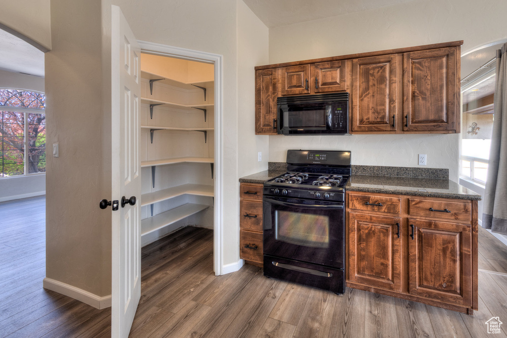 Kitchen featuring arched walkways, wood finished floors, baseboards, and black appliances