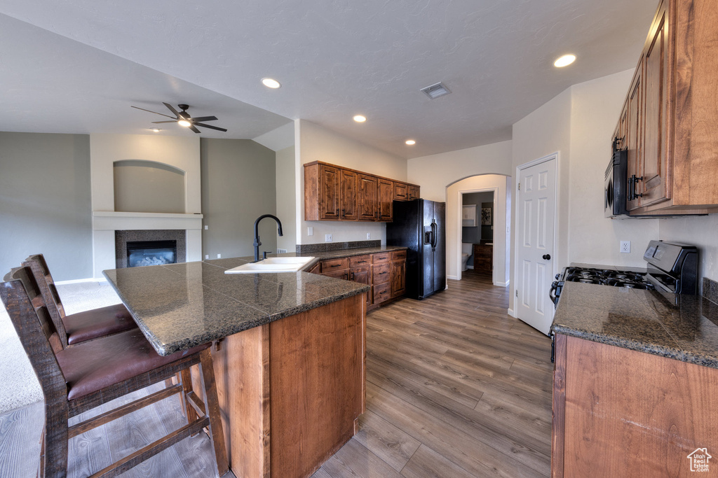 Kitchen with appliances with stainless steel finishes, a peninsula, ceiling fan, a sink, and wood finished floors