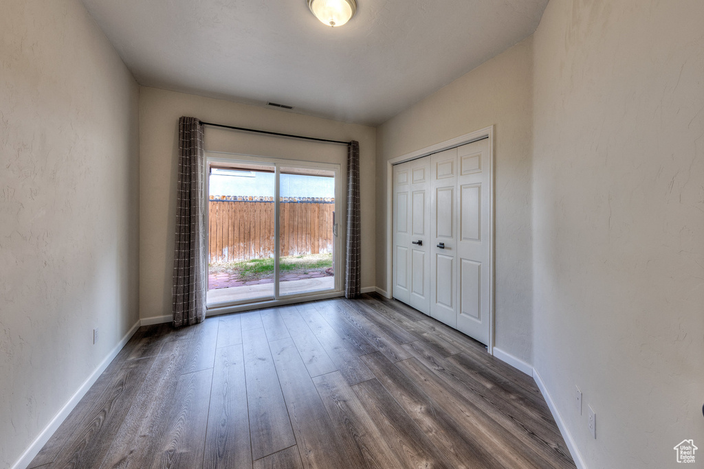 Spare room with dark wood-type flooring, visible vents, and baseboards