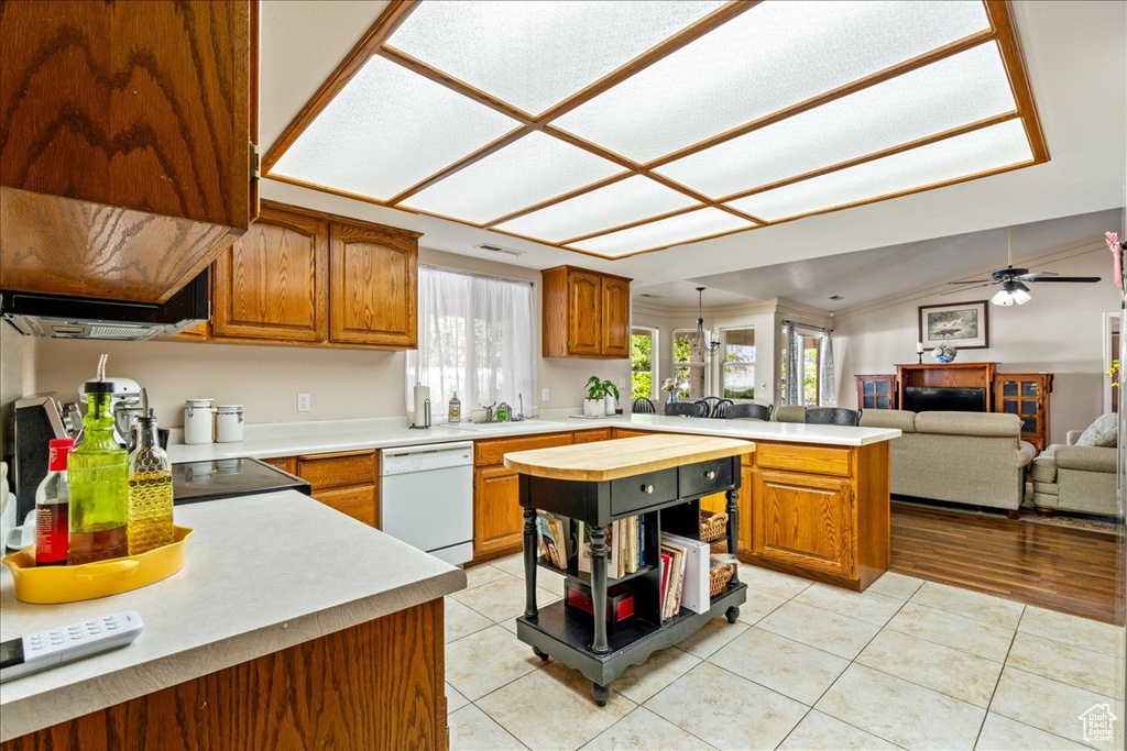 Kitchen with brown cabinetry, a peninsula, dishwasher, and light tile patterned floors