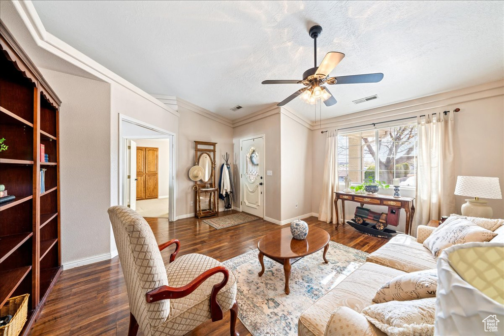 Living area with dark wood-type flooring, visible vents, ceiling fan, and baseboards