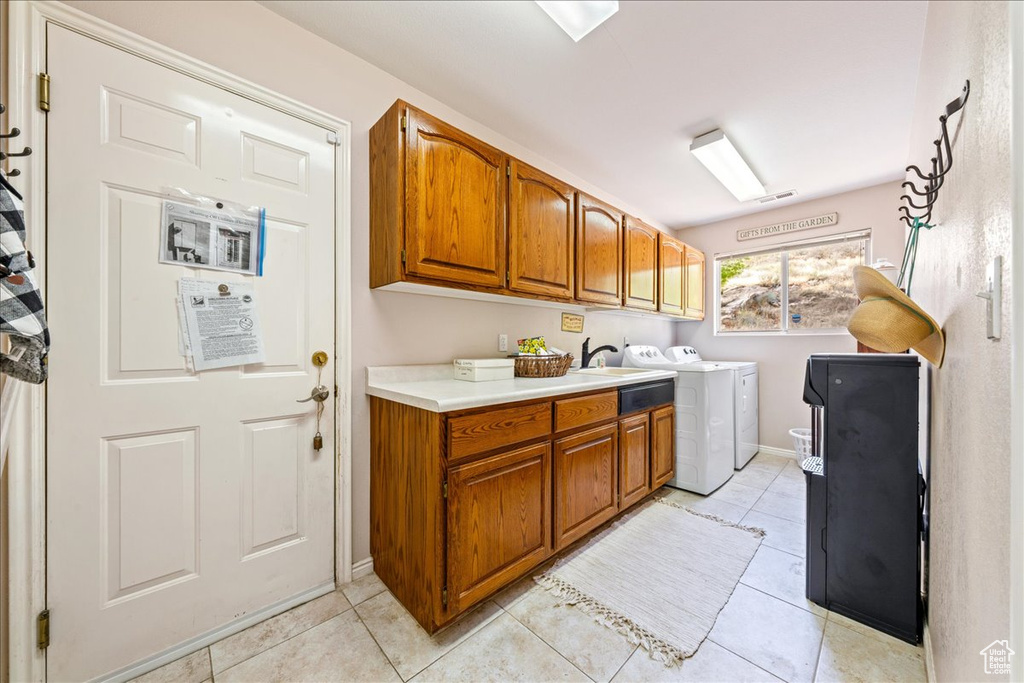 Laundry area featuring cabinet space, baseboards, washer and dryer, and light tile patterned flooring