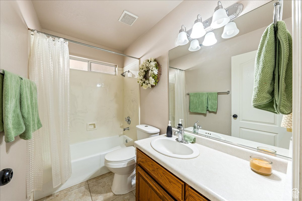 Full bath featuring vanity, tile patterned floors, toilet, visible vents, and shower / bath combo with shower curtain