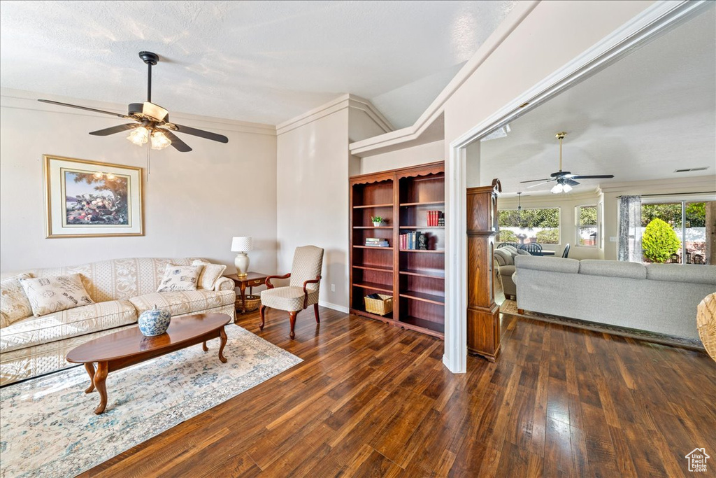 Living room featuring crown molding, a ceiling fan, hardwood / wood-style floors, and lofted ceiling