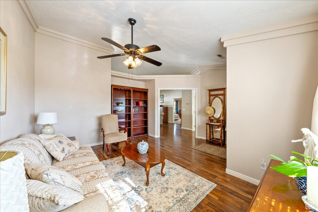 Living room featuring ornamental molding, ceiling fan, wood finished floors, and baseboards