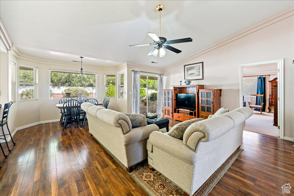 Living area featuring baseboards, dark wood-type flooring, vaulted ceiling, and a ceiling fan
