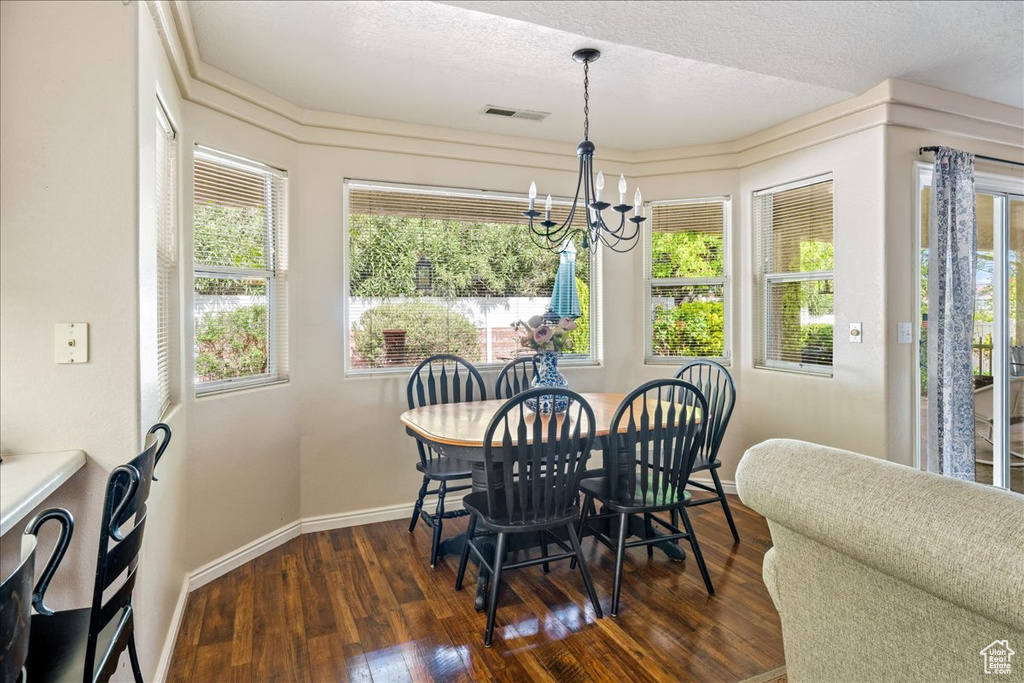 Dining space featuring visible vents, a healthy amount of sunlight, an inviting chandelier, and dark wood-style floors