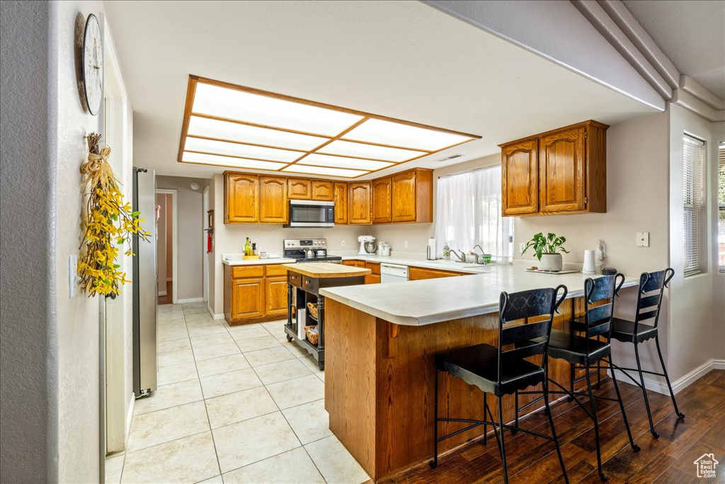 Kitchen featuring brown cabinets, light countertops, a peninsula, and stainless steel appliances