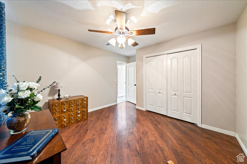 Interior space featuring a closet, baseboards, a textured ceiling, and wood finished floors