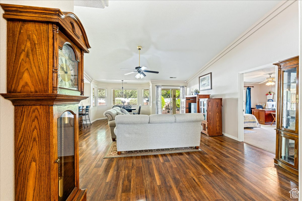 Living area featuring dark wood finished floors, baseboards, ornamental molding, and ceiling fan