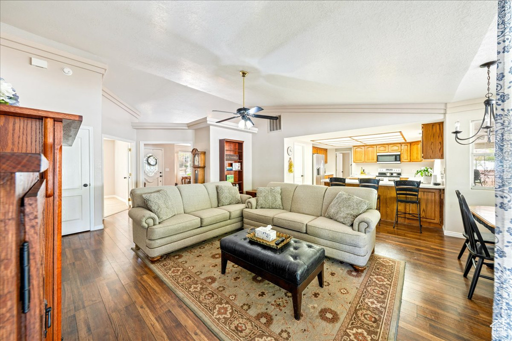 Living area featuring ceiling fan, dark wood-type flooring, a textured ceiling, visible vents, and lofted ceiling