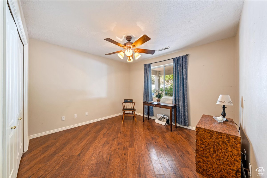Sitting room with dark wood-type flooring, a textured ceiling, a ceiling fan, visible vents, and baseboards