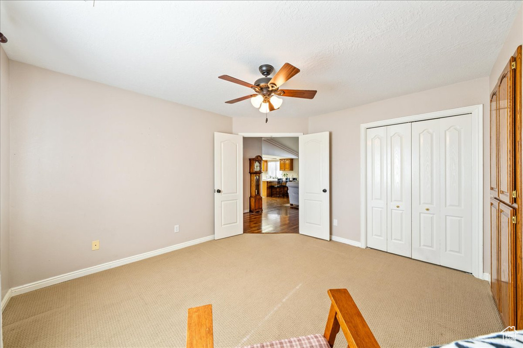 Unfurnished bedroom featuring light carpet, baseboards, a closet, and a ceiling fan