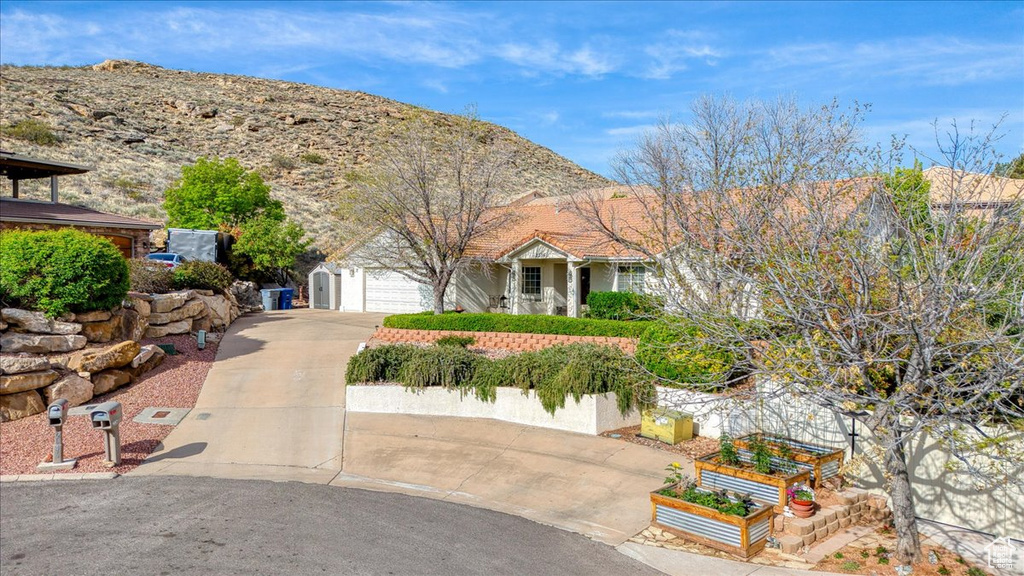 View of front facade with concrete driveway, a garden, and an attached garage