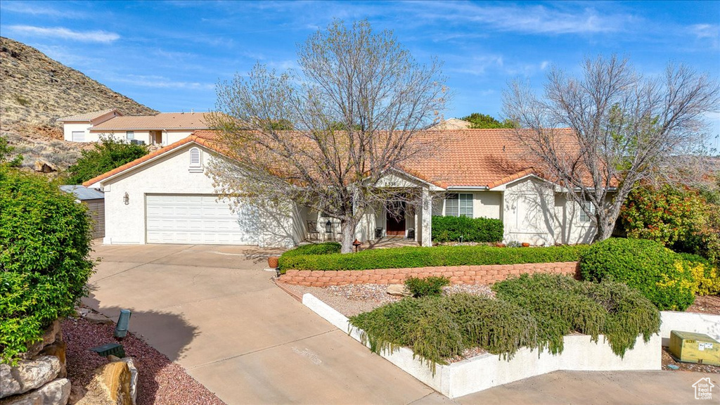 View of front of house featuring an attached garage, driveway, stucco siding, and a tile roof
