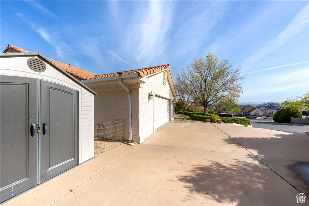 Exterior space featuring a tile roof, an outdoor structure, and stucco siding