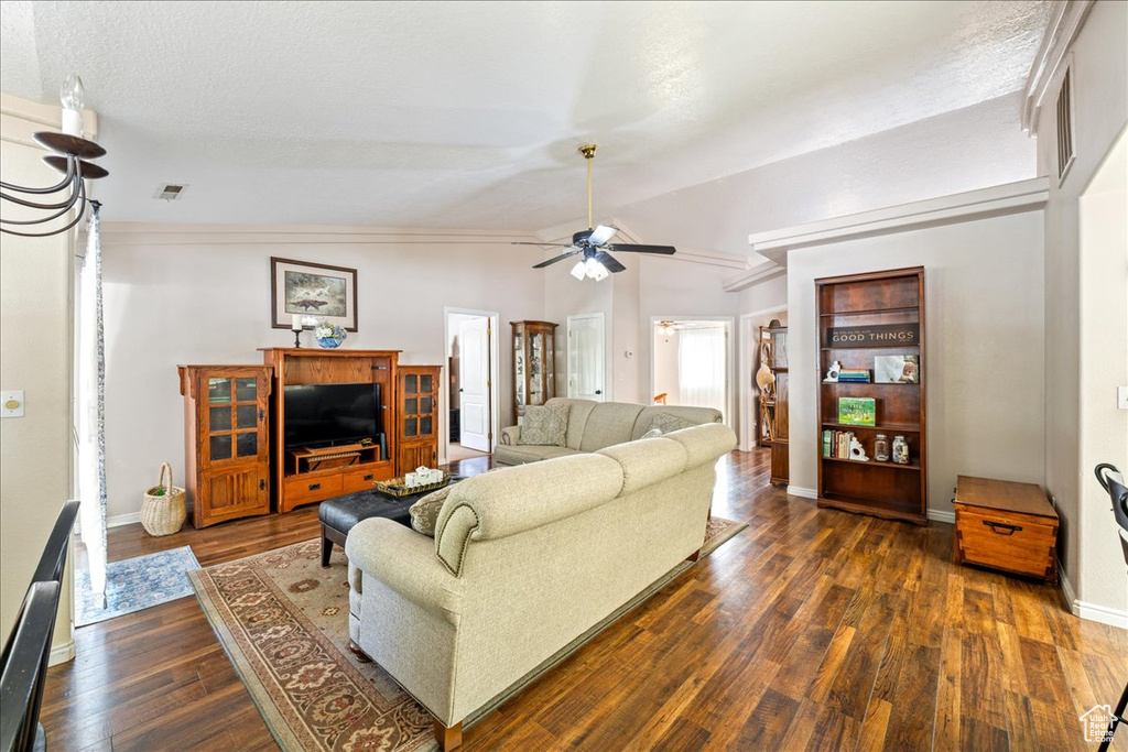 Living room with dark wood-style flooring, baseboards, vaulted ceiling, a ceiling fan, and visible vents