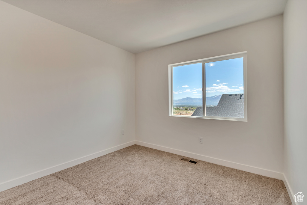 Spare room featuring baseboards, light carpet, and visible vents