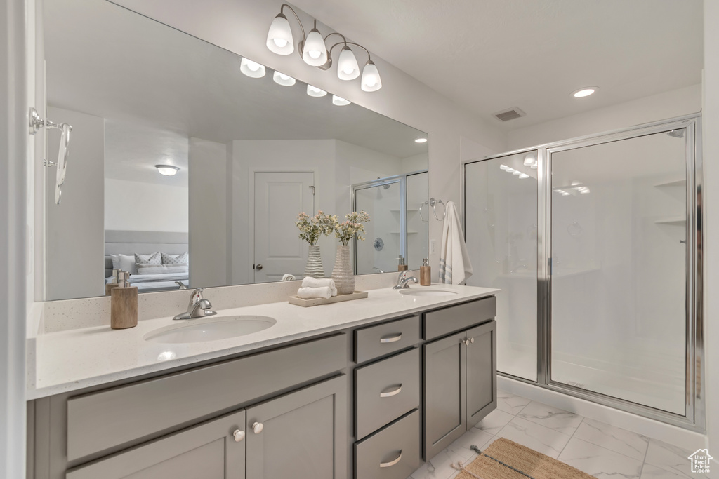 Bathroom with a shower stall, marble finish floor, double vanity, and a sink