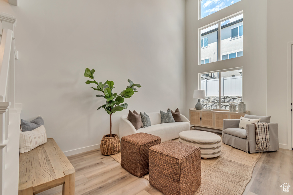 Living room featuring baseboards, light wood finished floors, and a towering ceiling