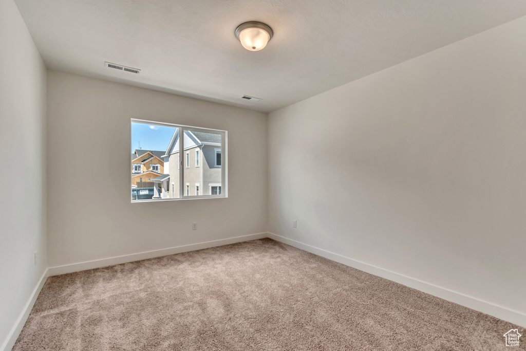 Empty room featuring baseboards, visible vents, and carpet floors