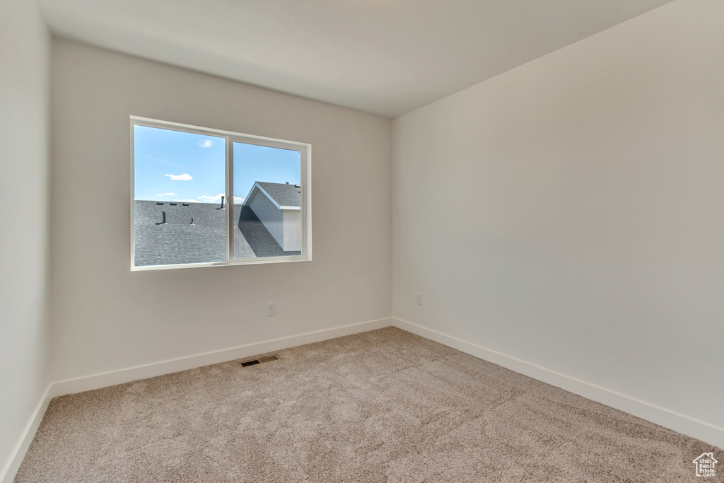 Carpeted empty room with visible vents and baseboards