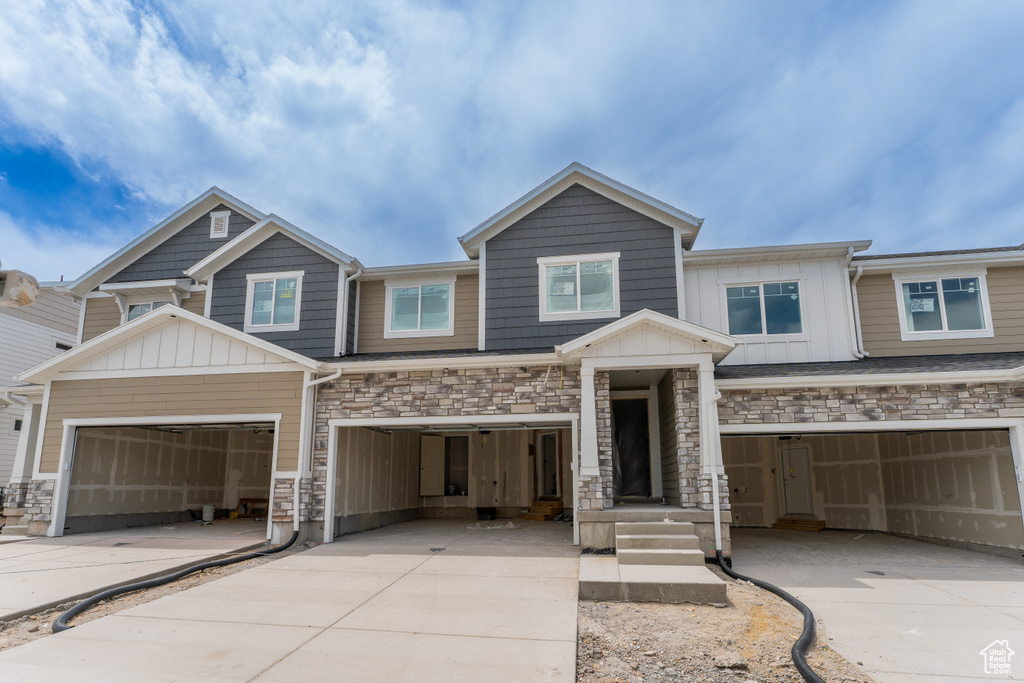View of front of house featuring concrete driveway, stone siding, board and batten siding, and a garage