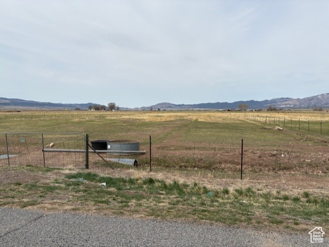 View of yard with a rural view, a mountain view, and fence