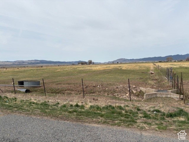 View of yard featuring a rural view, a mountain view, and fence