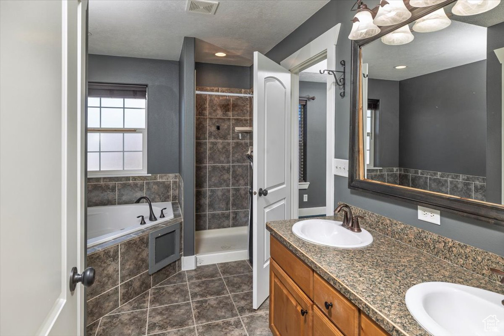 Bathroom with a shower stall, a garden tub, a sink, and visible vents