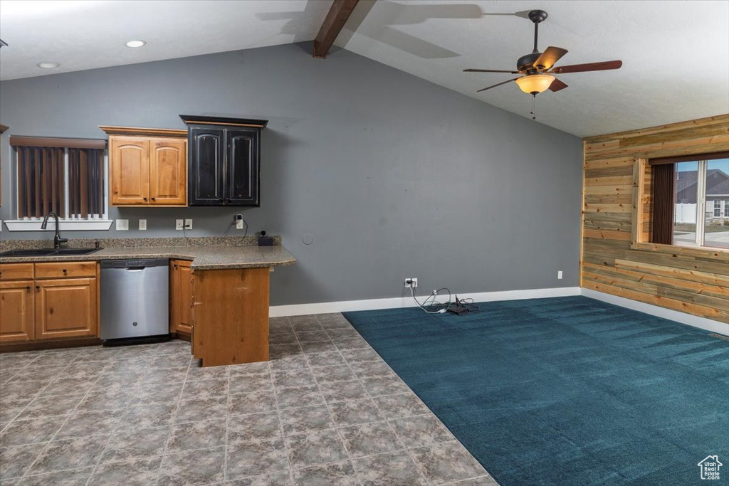 Kitchen featuring lofted ceiling with beams, a sink, ceiling fan, wood walls, and stainless steel dishwasher