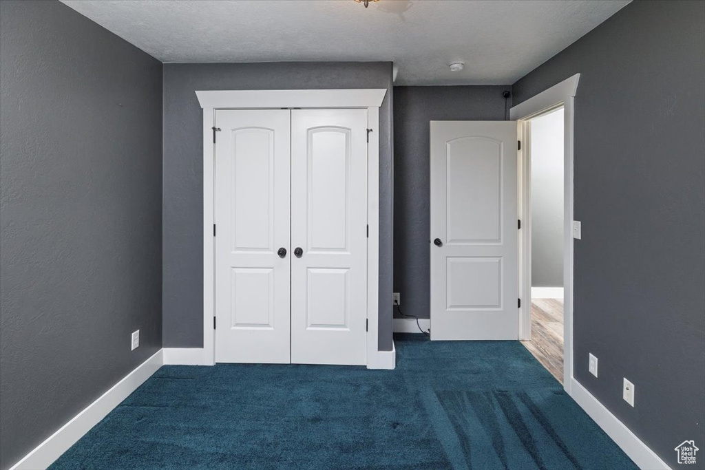 Unfurnished bedroom with a closet, baseboards, and dark carpet