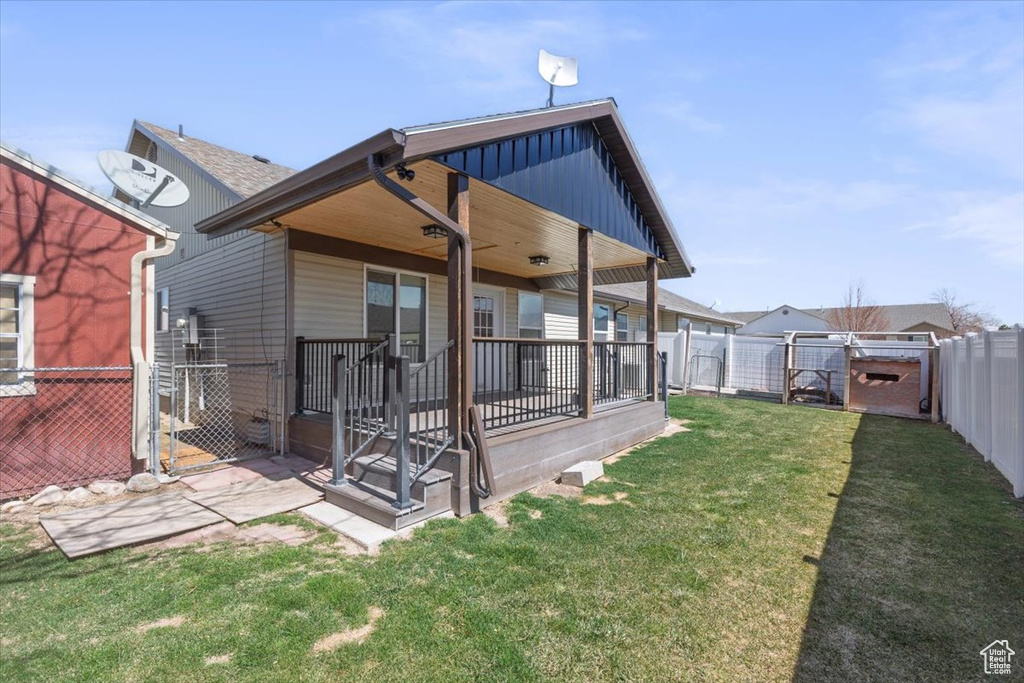Back of property with board and batten siding, a yard, a fenced backyard, and a gate