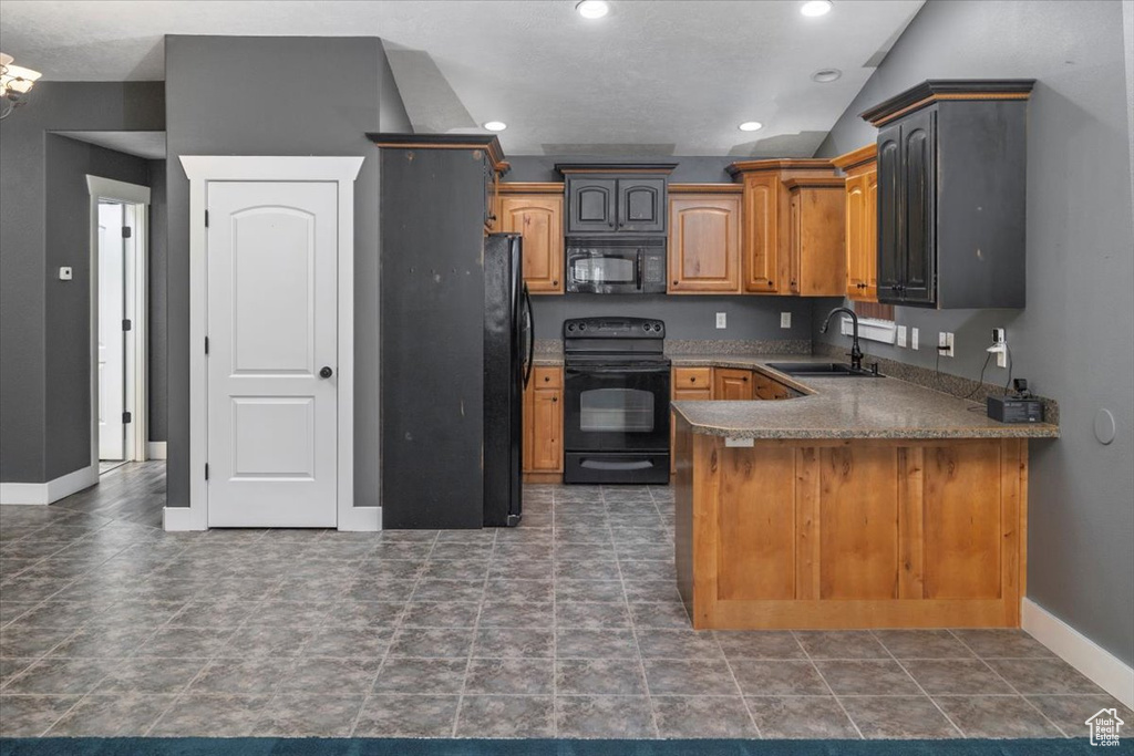 Kitchen featuring baseboards, recessed lighting, a peninsula, black appliances, and a sink