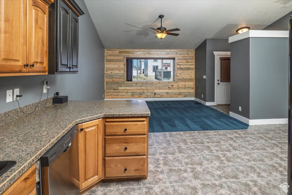 Kitchen with ceiling fan, a peninsula, an accent wall, wood walls, and dishwasher