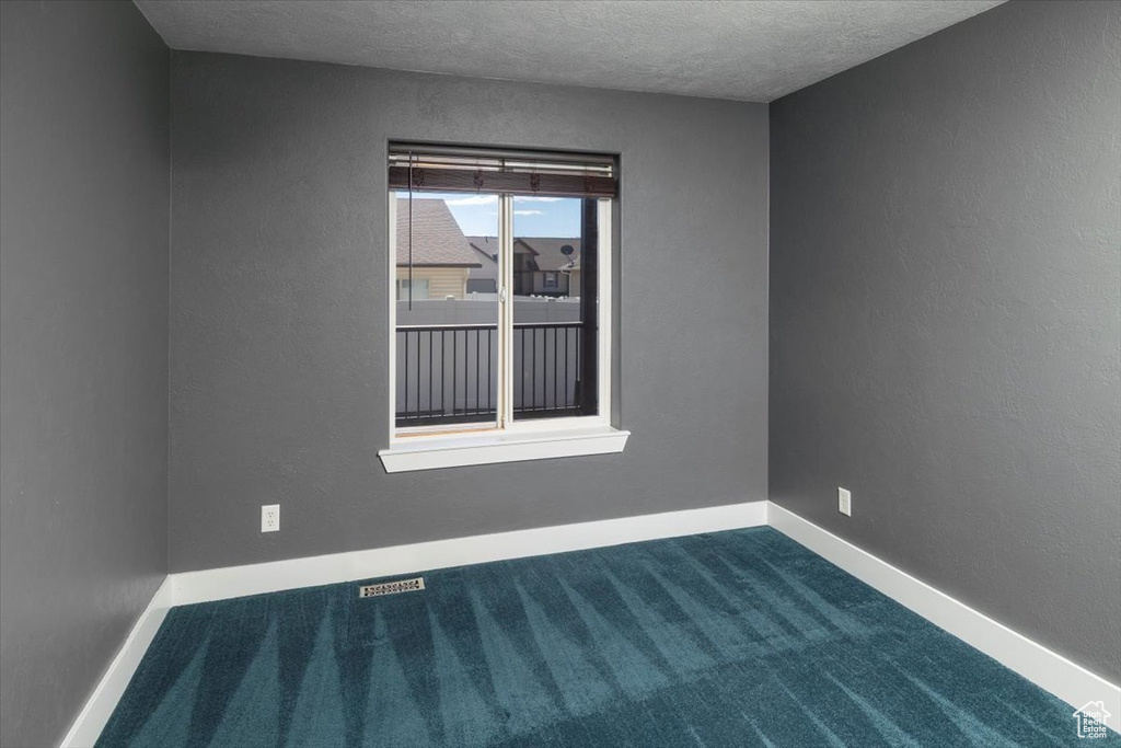 Unfurnished room with dark carpet, a textured ceiling, baseboards, and visible vents
