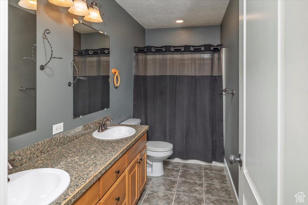 Bathroom featuring a sink, toilet, double vanity, and tile patterned flooring