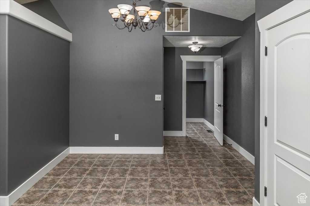 Unfurnished dining area featuring baseboards, a notable chandelier, vaulted ceiling, and visible vents