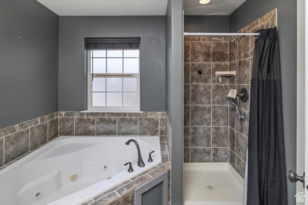 Bathroom featuring a whirlpool tub and a stall shower