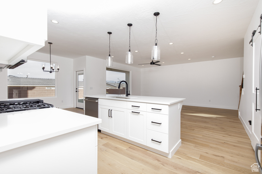 Kitchen with a sink, decorative light fixtures, light wood-style floors, and ceiling fan with notable chandelier
