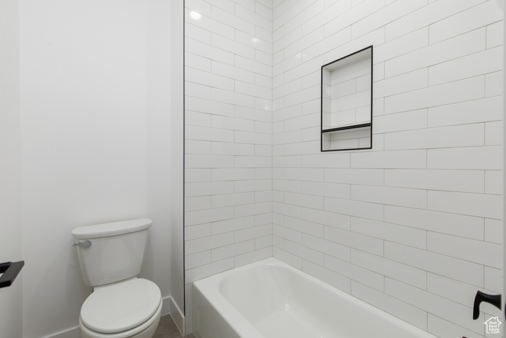 Full bath featuring toilet, baseboards, and  shower combination