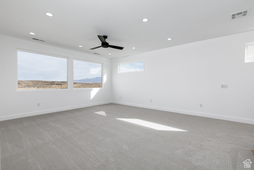 Spare room featuring light carpet, a ceiling fan, and visible vents