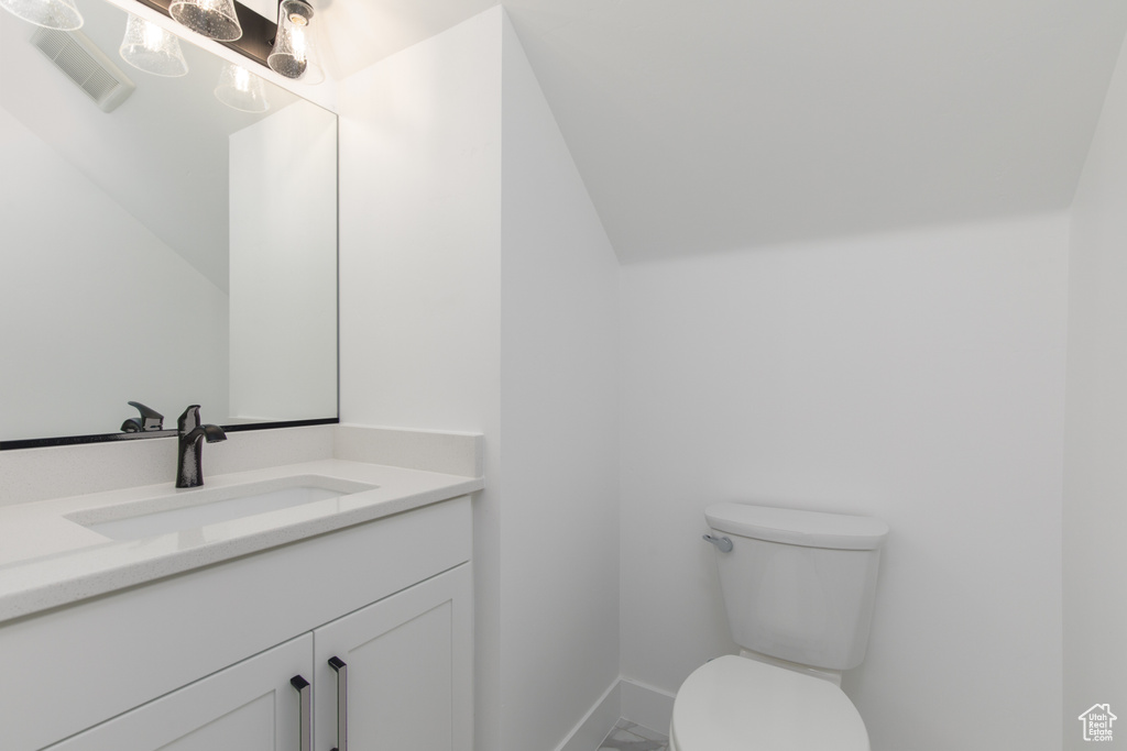 Bathroom with toilet, vanity, and baseboards