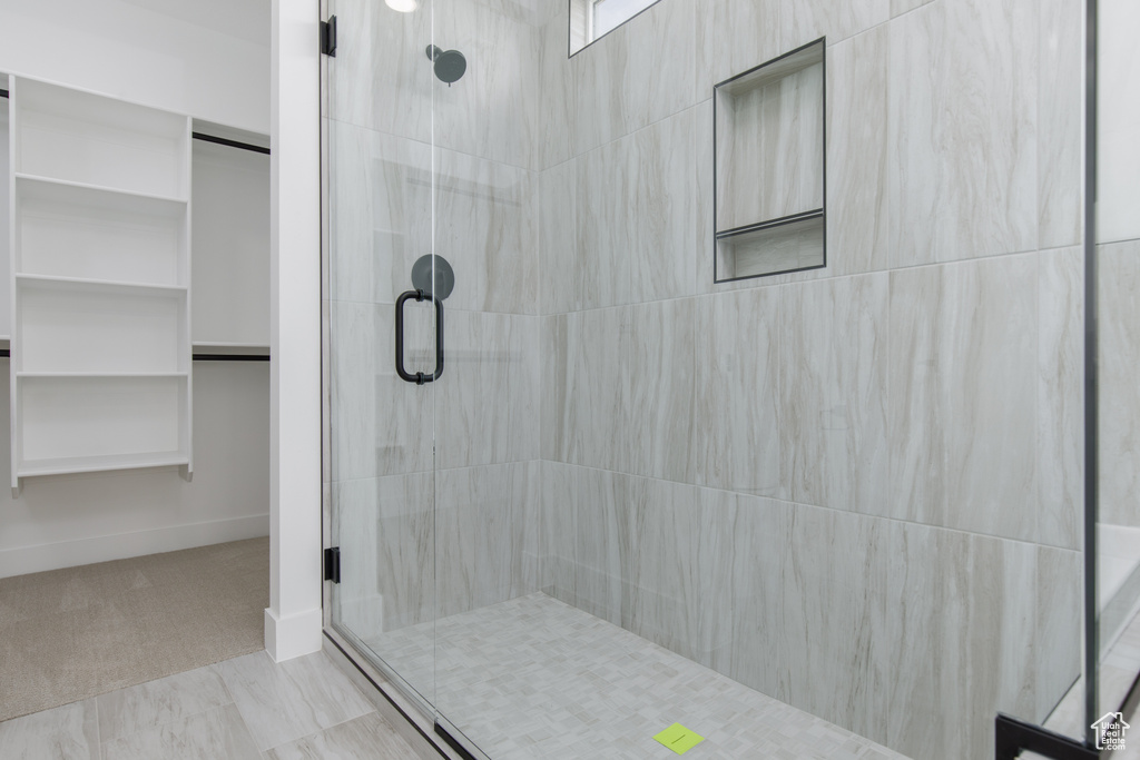 Full bath with a tile shower, baseboards, and a walk in closet
