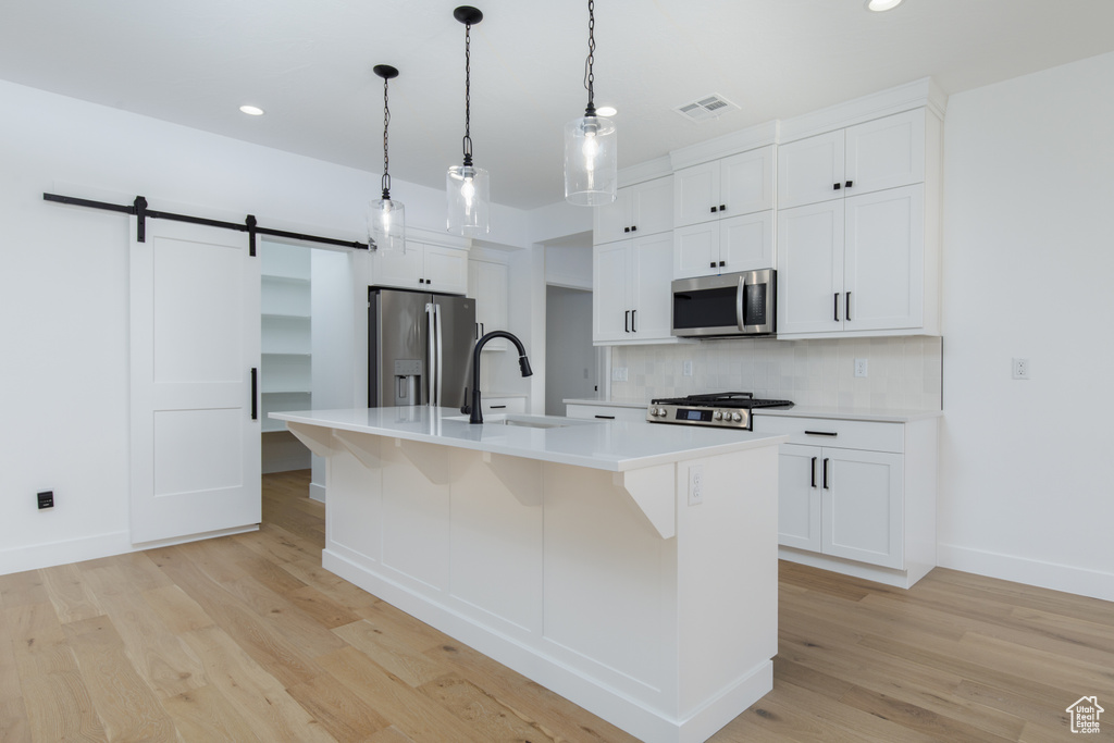 Kitchen with a sink, decorative backsplash, light wood-style floors, and stainless steel appliances