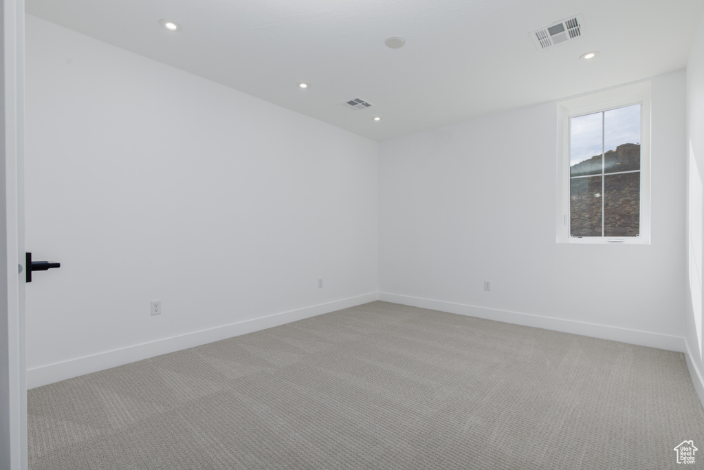 Empty room with light colored carpet, baseboards, and visible vents
