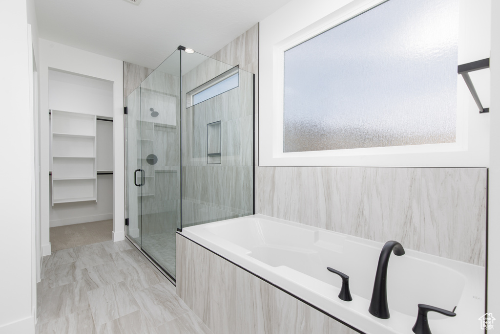 Bathroom with a shower stall, a bath, and a spacious closet