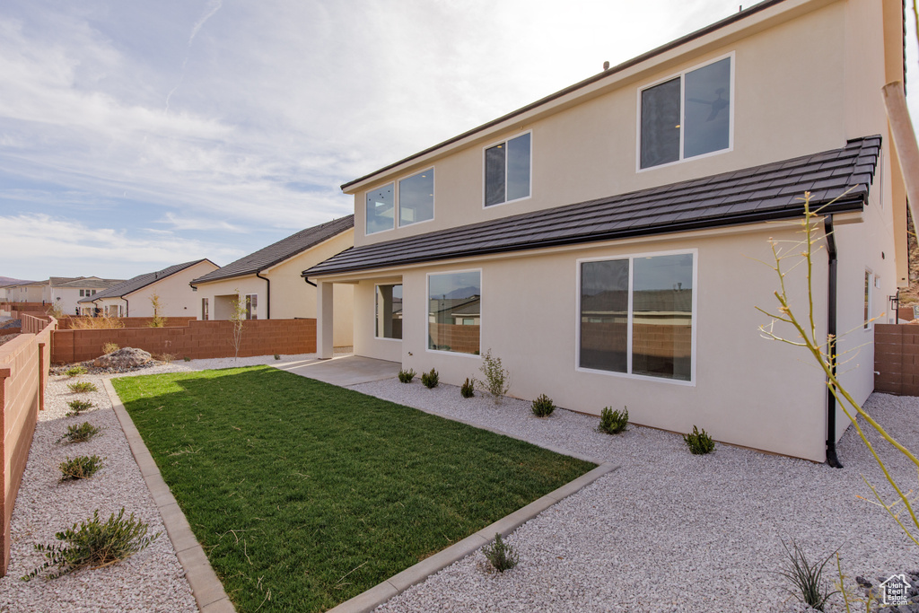Back of house with a yard, stucco siding, and a fenced backyard