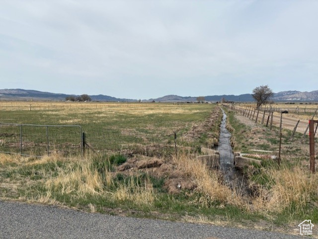 View of yard with a rural view, a mountain view, and fence