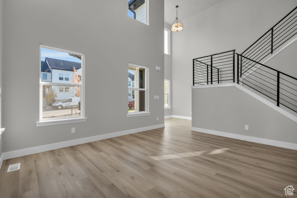 Unfurnished living room featuring wood finished floors, baseboards, plenty of natural light, and stairway